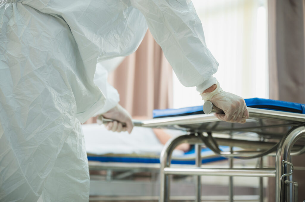 professional doctors in the full protective suits and surgical masks are examining the infected patient in the hospital control area